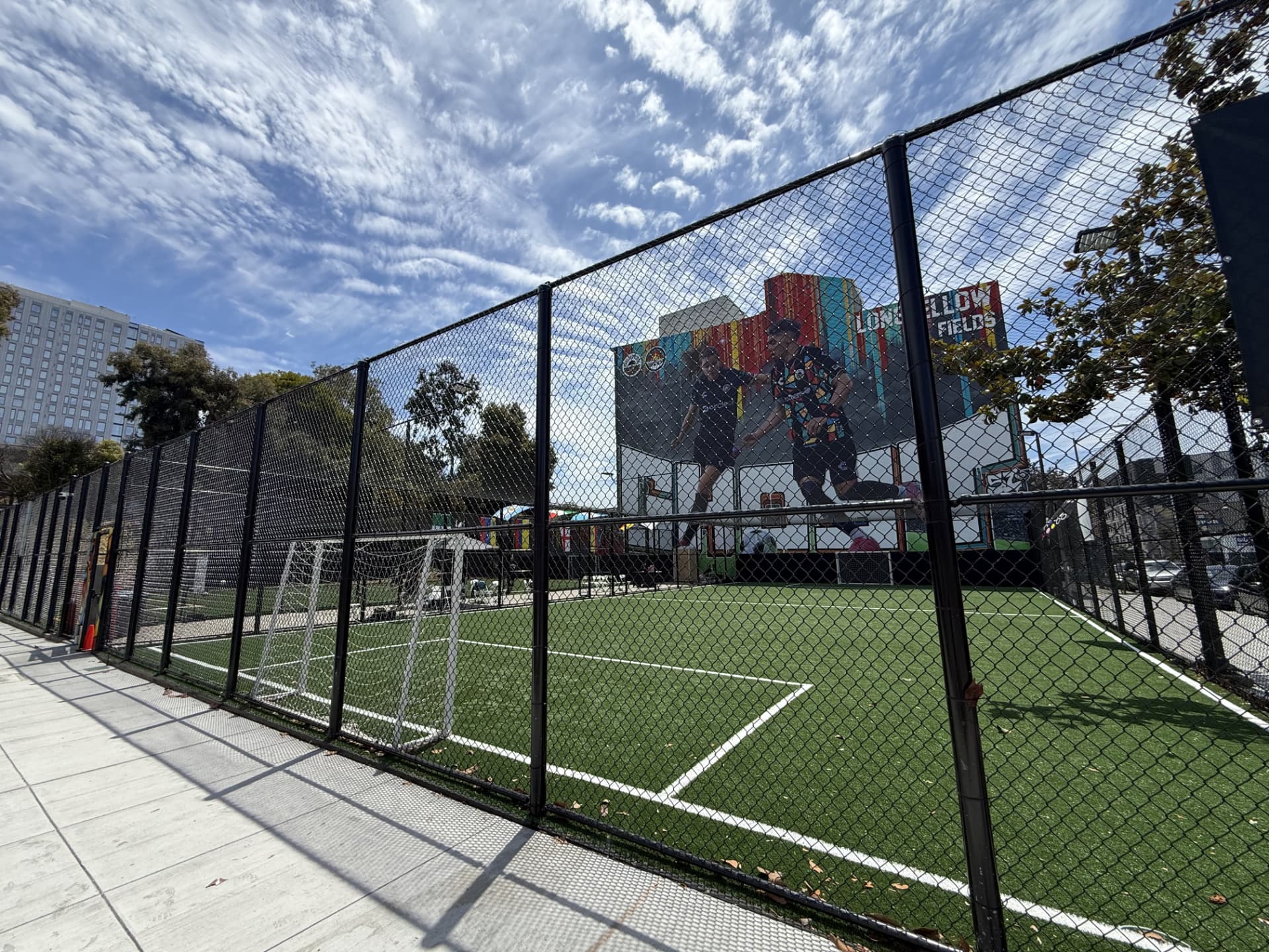 The turf pitch and goal at Longfellow Fields viewed through the black perimeter fencing