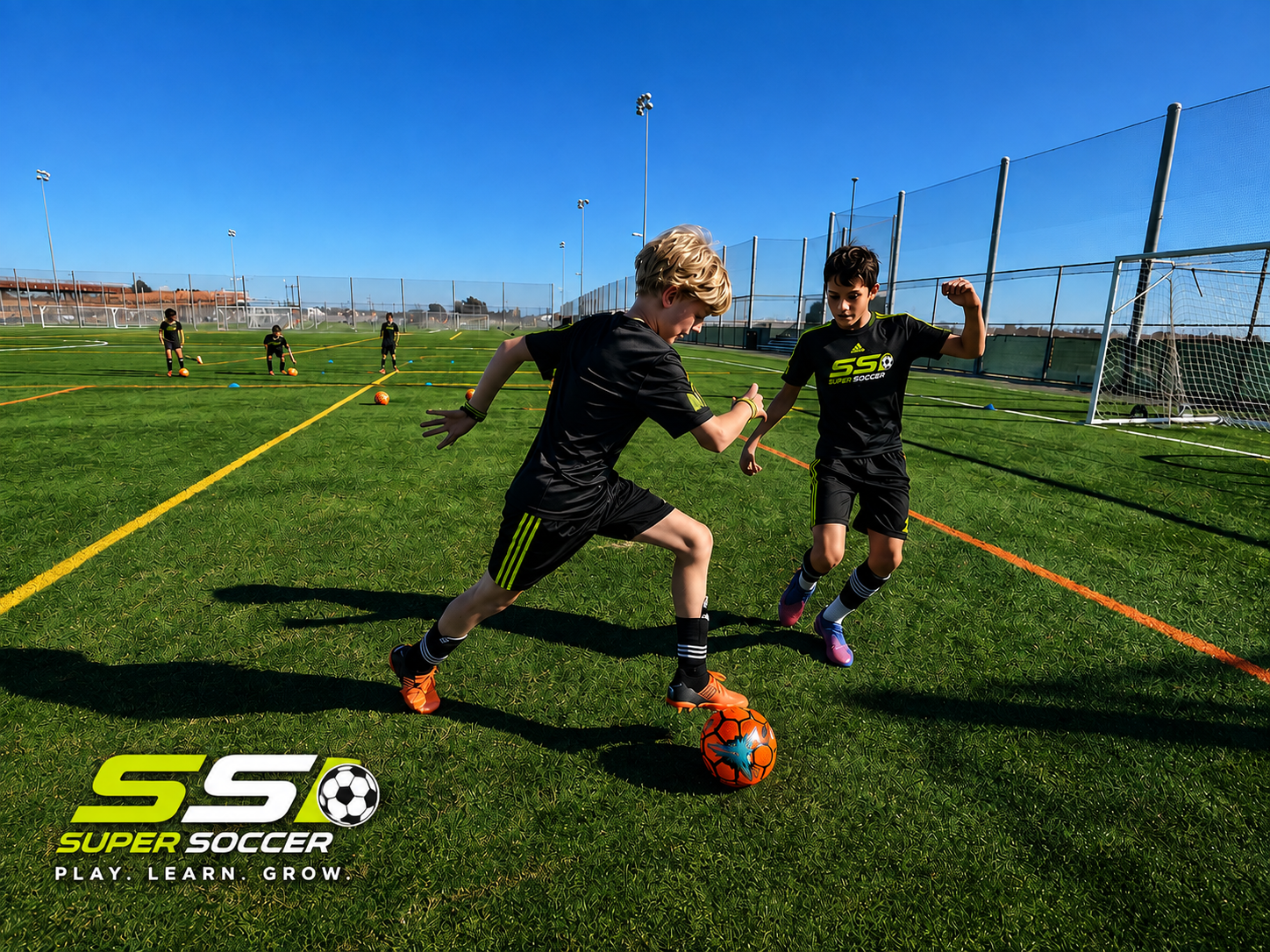 Two Super Soccer players in black and lime kits battling for the ball on the turf at Longfellow Fields